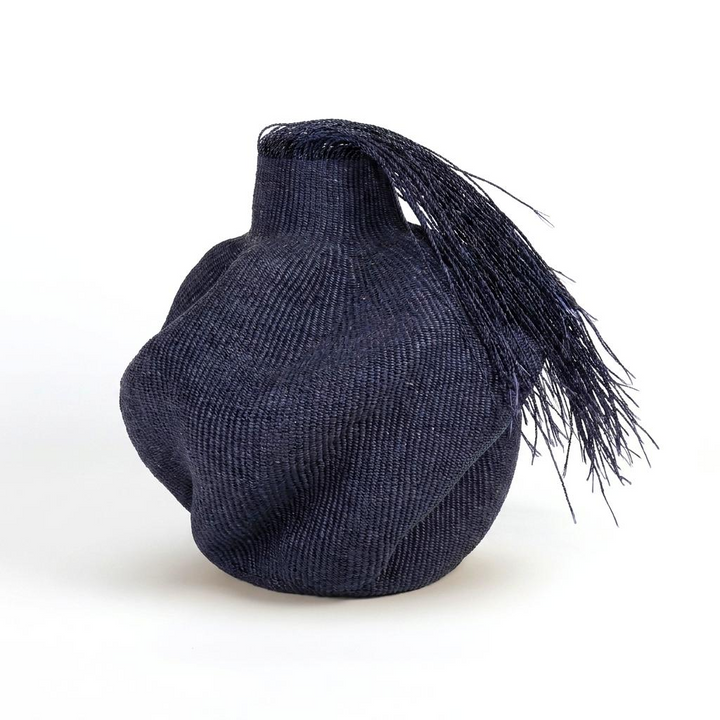 Hairy black wavy sculptural basket with a long fringe falling from its collar, on white