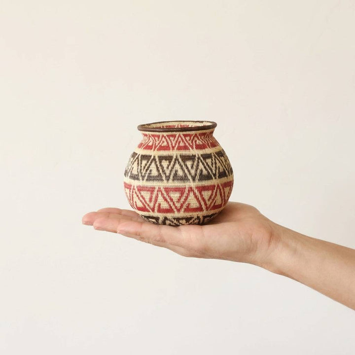 Small crimson palm fiber basket with triad geometric pattern handwoven by indigenous artisans