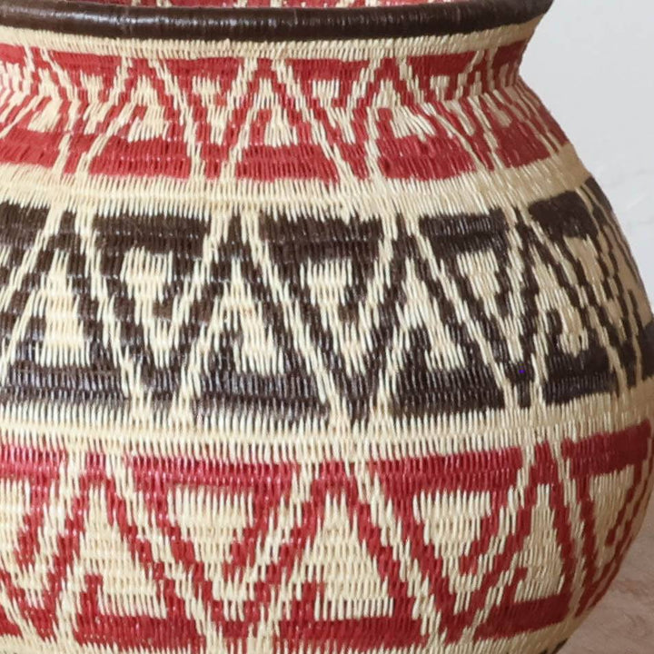 Close-up detail of tight palm fiber weaving showing crimson dyed strands in geometric triad pattern