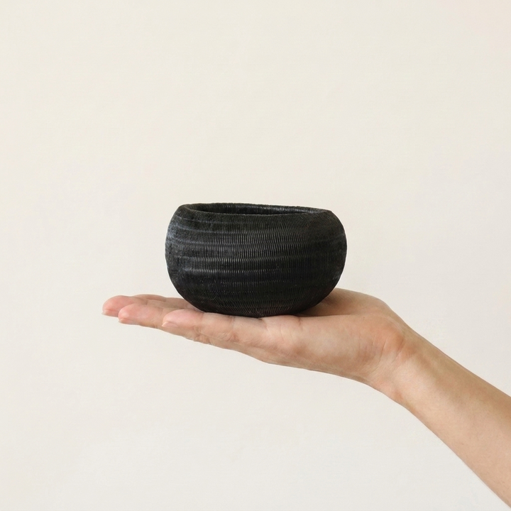 Midnight Coil Mini Basket, one of one werregue basket handwoven by Wounaan weavers in Chocó, Colombia, held in hand for scale
