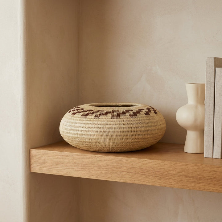 Earth Steps Disc, one of one werregue basket handwoven by Wounaan weavers in Chocó, Colombia, styled on a shelf