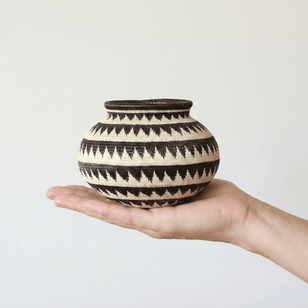 Black and cream handwoven Wounaan basket held in hand showing miniature scale, about five inches wide