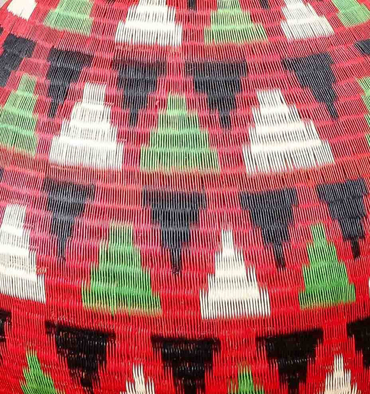 Close-up of tight palm fiber weave showing crimson dye and traditional basket craftsmanship techniques