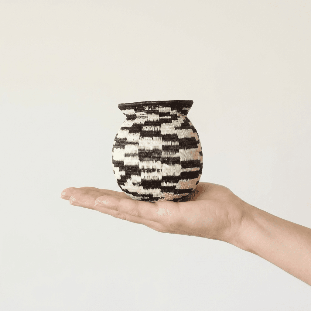 Black and white checkered Wounaan basket held in hand showing miniature scale, about two inches wide