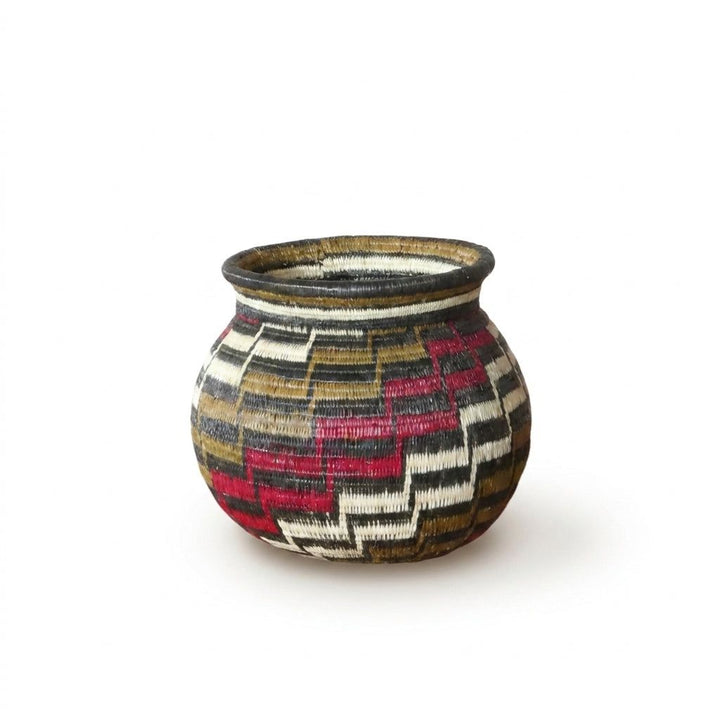 Mini Wounaan basket showing interlocking red, brown, black and white stair-step motif in woven palm fiber