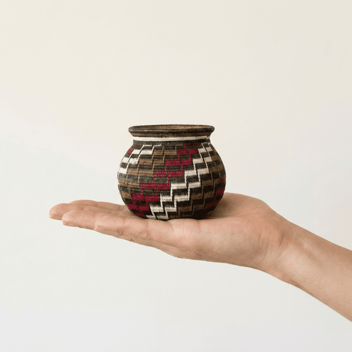 Colorful stepped-pattern handwoven Wounaan basket held in hand showing miniature scale, about three inches
