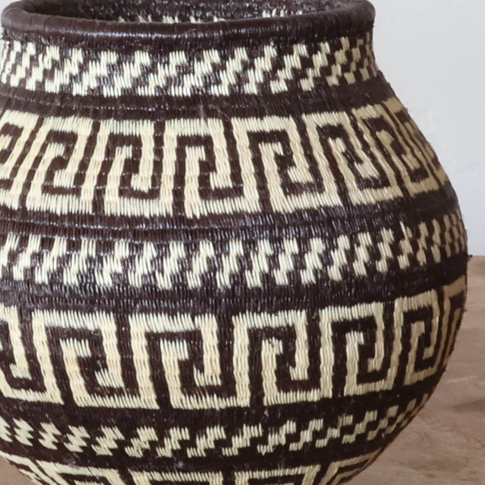 Close-up of a woven basket with a brown and cream Greek-key maze pattern