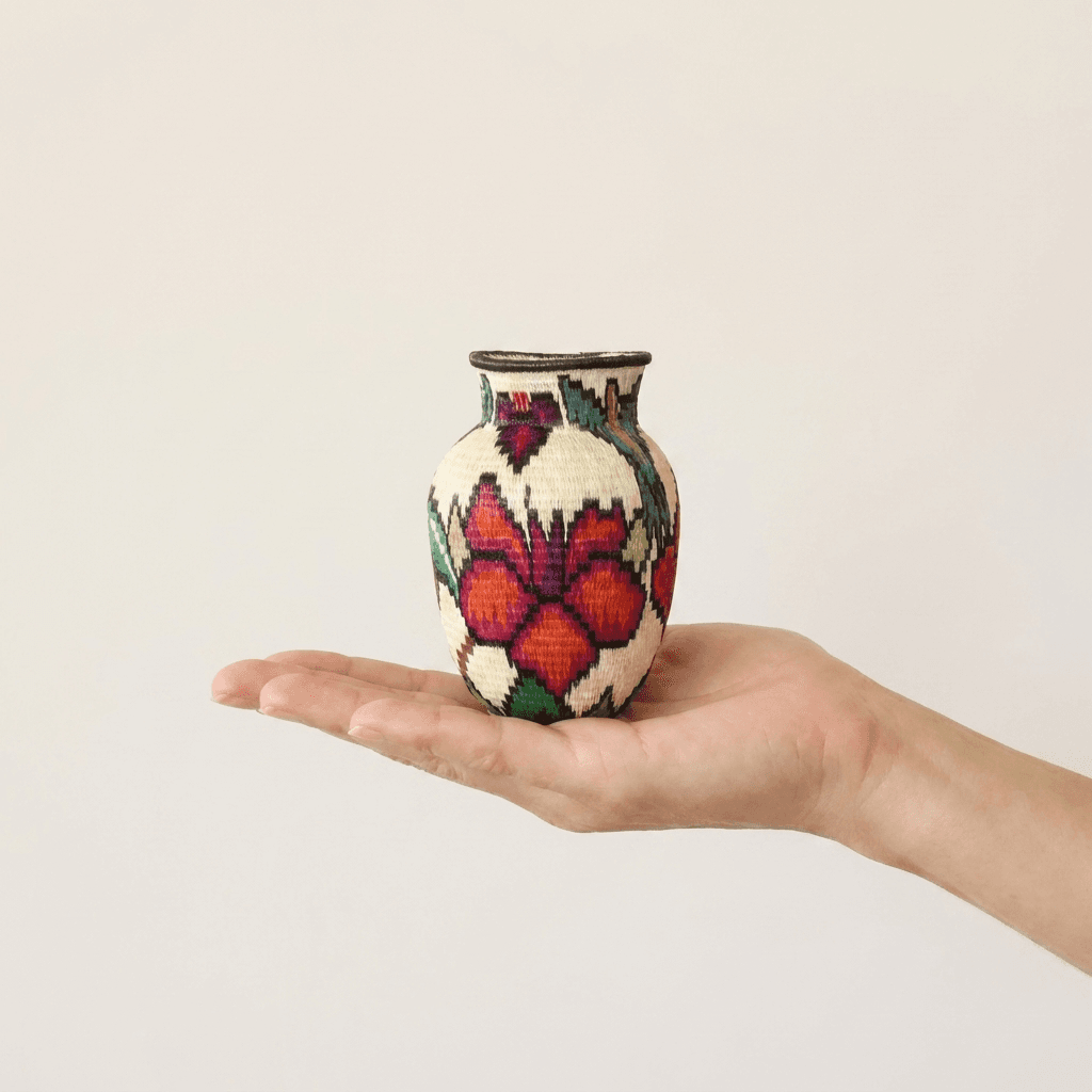 Colorful floral Wounaan basket held in hand showing miniature scale, orange-red blossoms about three inches tall