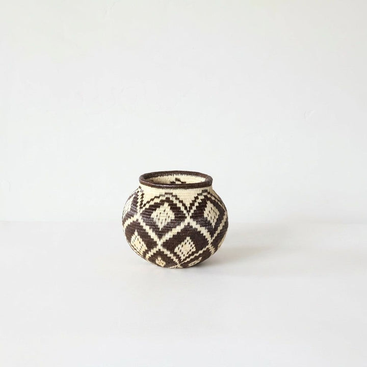 Black and cream diamond-pattern handwoven Wounaan basket shown full view with dark coiled rim