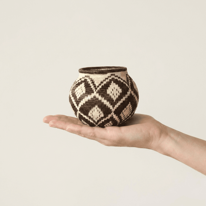 Diamond-pattern handwoven Wounaan basket held in hand showing miniature scale, about four inches wide