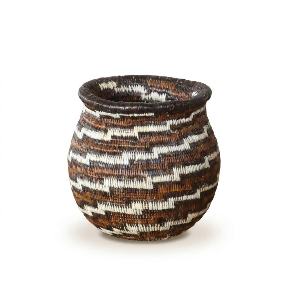 Close view of miniature Wounaan basket showing diagonal staircase swirl in warm brown, rust and ivory palm fiber