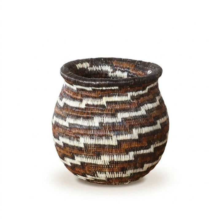 Close view of miniature Wounaan basket showing diagonal staircase swirl in warm brown, rust and ivory palm fiber