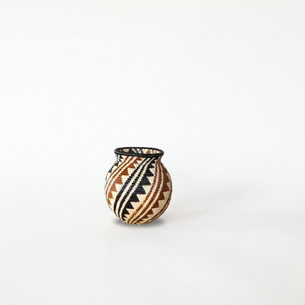 Handwoven Wounaan basket with diagonal black and rust sawtooth spiral bands on cream, black rim, from Panama