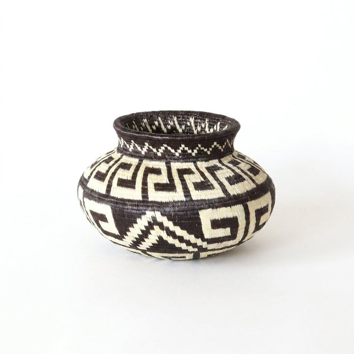 Side view of interlocking black and cream fret maze on miniature handwoven Wounaan basket from Panama