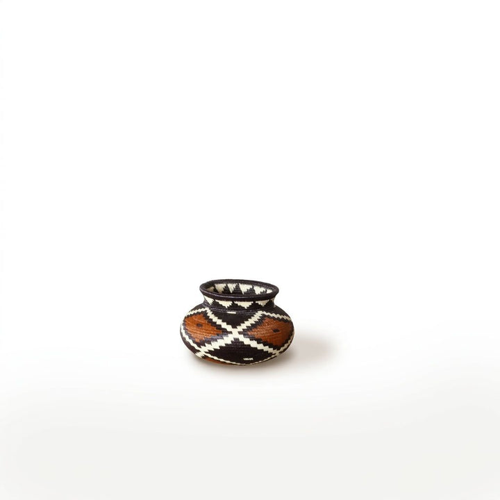 Tiny Wounaan handwoven basket with rust and black diamond lattice shown small against a white background