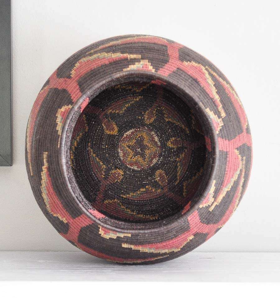Top view of handmade Panama basket showing depth and dimensional heliconia flower pattern against black background