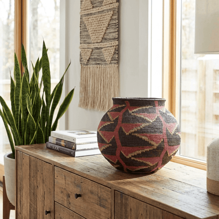 black woven basket with vibrant heliconia flower patterns displayed in modern tribal interior