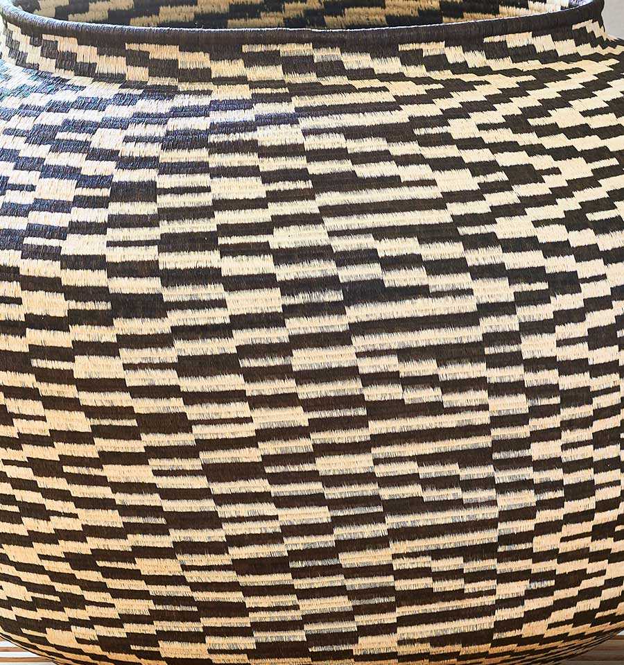 Close-up detail of black and white palm fiber weaving showing intricate cultural pattern work