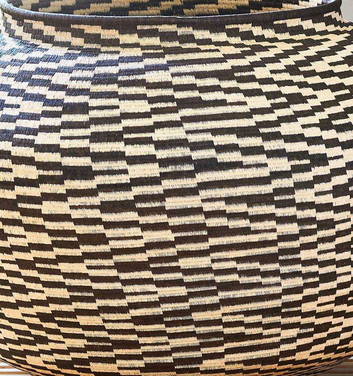 Close-up detail of black and white palm fiber weaving showing intricate cultural pattern work