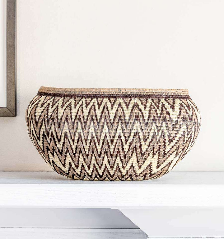 Close-up of tight palm fiber weave showing grey chevron geometric pattern detail in oval basket