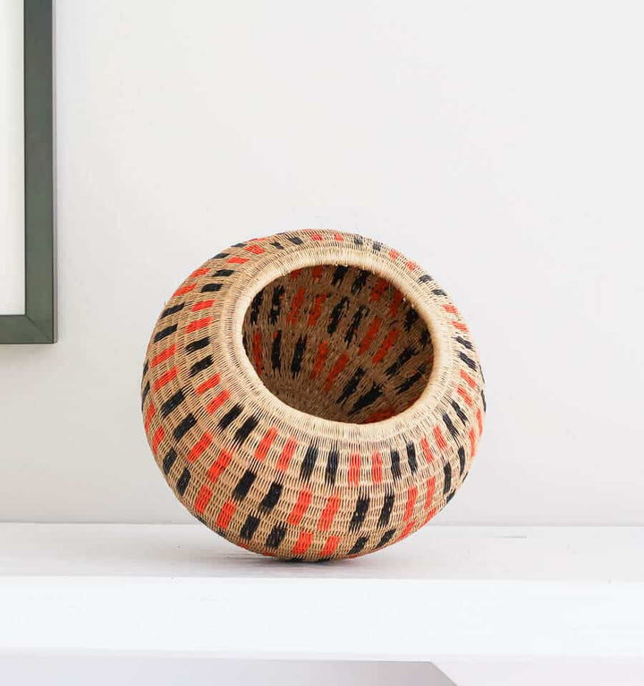 Handwoven decorative basket with orange and black geometric dash pattern by indigenous artisans