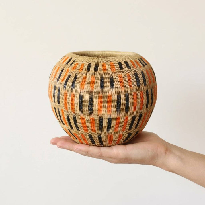 Handwoven decorative basket with orange and black geometric dash pattern by indigenous artisans