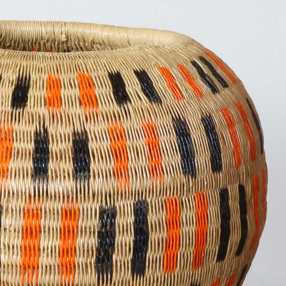 Close-up of tight palm fiber weave showing orange and black dash pattern craftsmanship detail