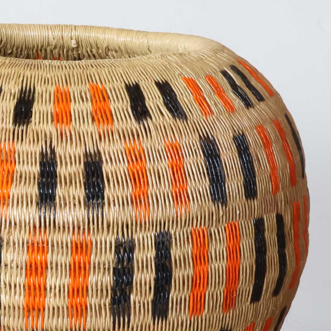 Close-up of tight palm fiber weave showing orange and black dash pattern craftsmanship detail
