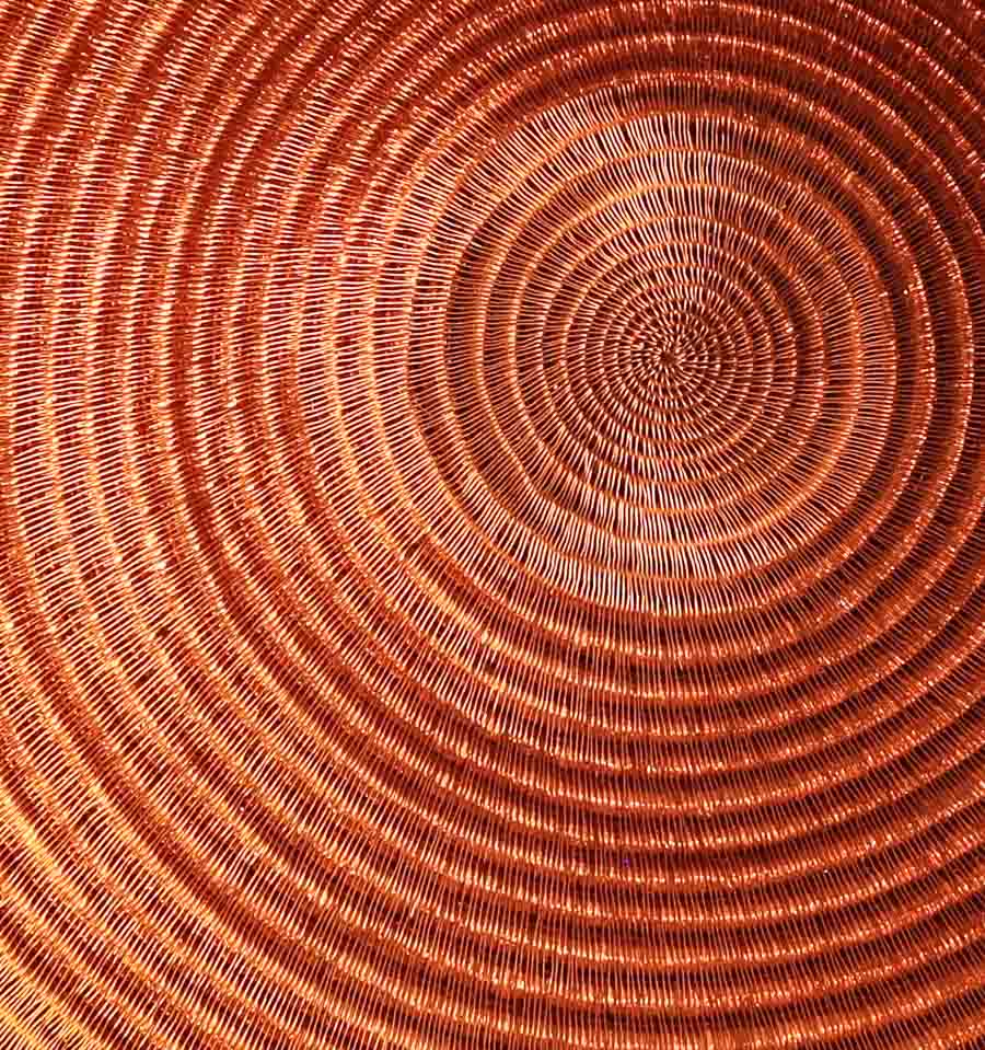 Close-up detail of tight palm fiber weaving showing molten gold color transitions in handwoven plate