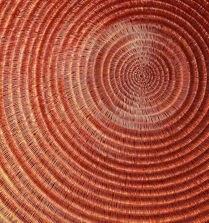 Close-up detail of tight palm fiber weaving showing molten gold color transitions in handwoven plate