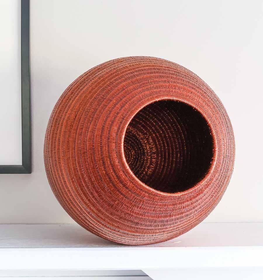 Side view of large decorative copper vessel basket showing sculptural vessel form