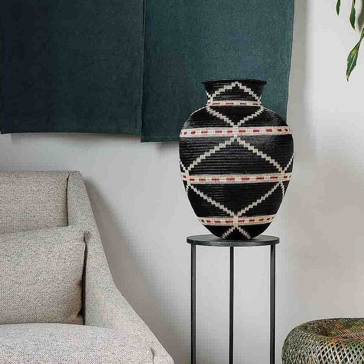 Handmade decorative basket with copper geometric motifs on dark woven palm fiber by Wounaan artisans from Colombia