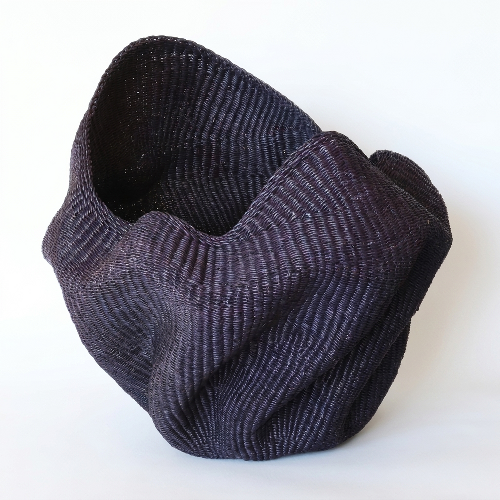 Indigo wavy sculptural basket with deep folded walls, on white