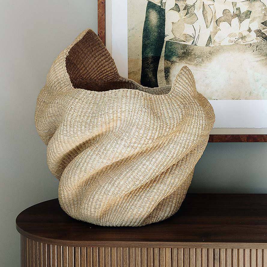 Sculptural handmade basket from Ghana shaped in flowing wave form using elephant grass