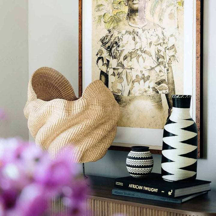 Rwandan woven basket displayed as sculptural decor on modern console table