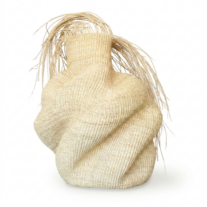 Sculptural natural woven vessel with a wild fibrous fringe on top, on white