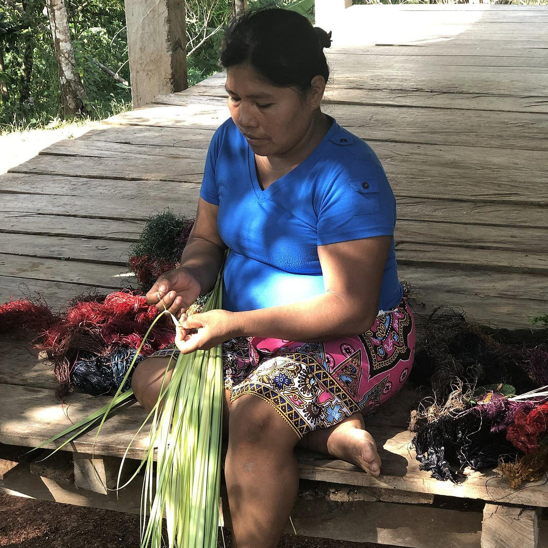 A Wounaan weaver peeling chunga fronds, dyed fiber drying beside her