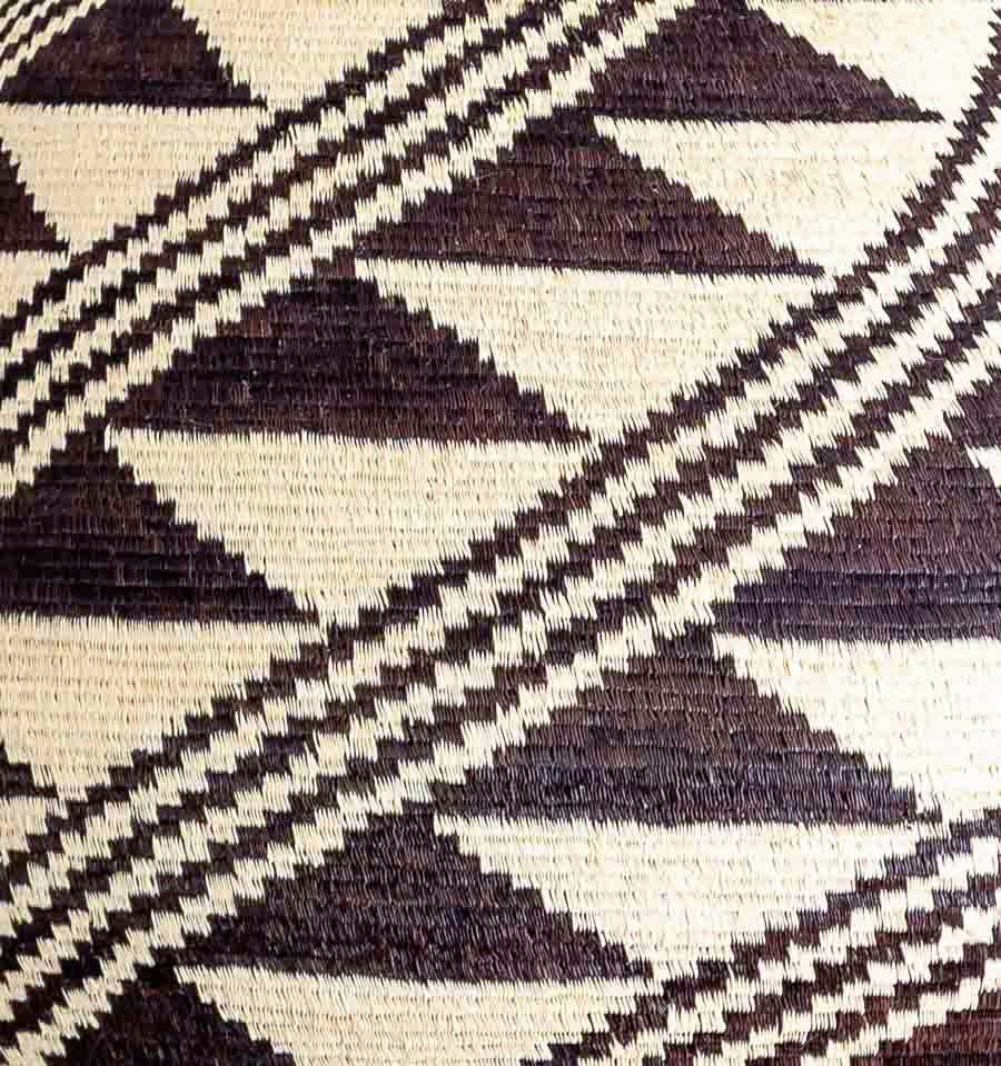 Close-up chunga palm weaving showing intricate black feather geometric patterns