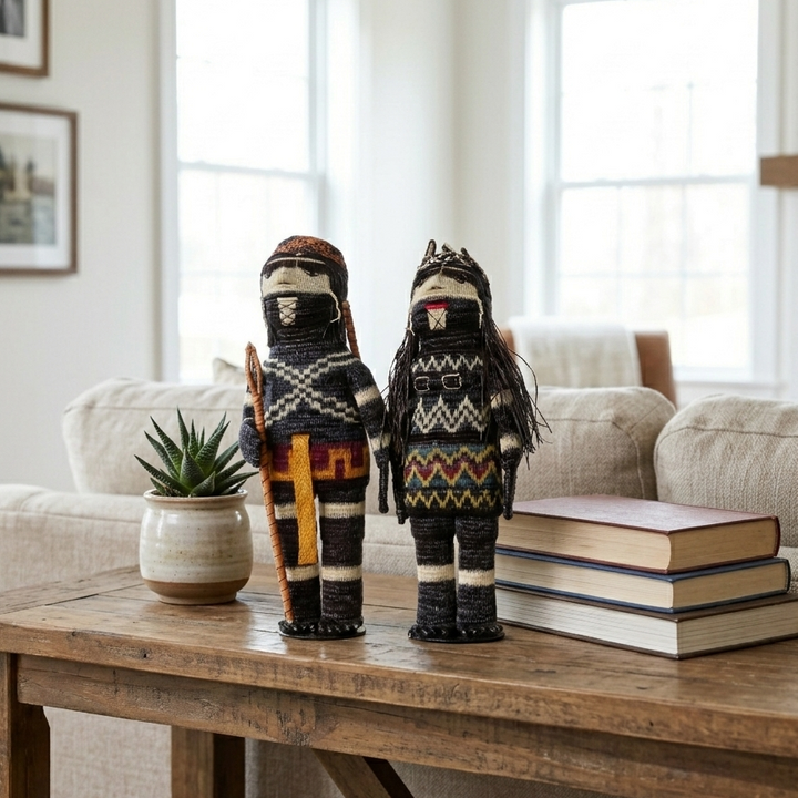 Two woven Embera dolls with patterned bodies displayed on a wood table with books