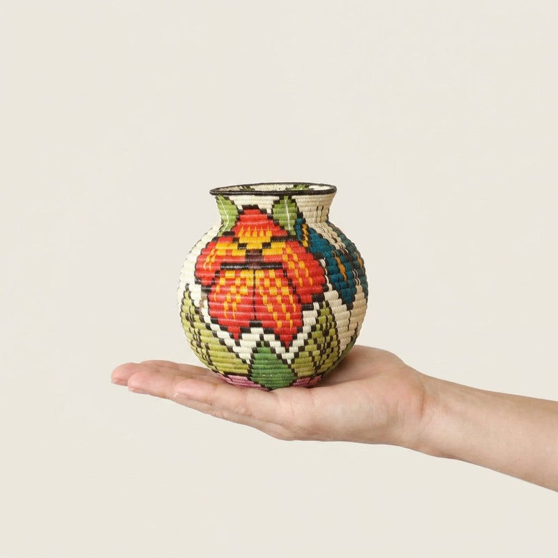 Mini butterfly garden Wounaan handwoven basket held in hand showing miniature scale, scarlet flower side