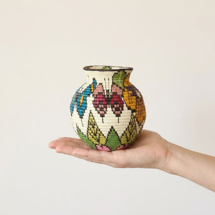Wounaan handwoven butterfly basket held in hand showing miniature scale, rose-pink butterfly and leaves