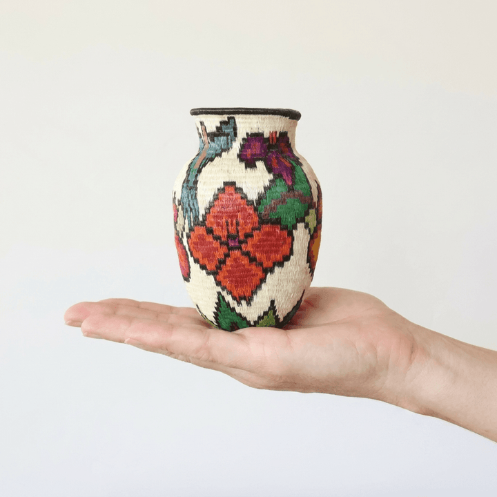 Mini Wounaan handwoven garden basket held in hand showing miniature scale, hummingbird and red flowers on cream
