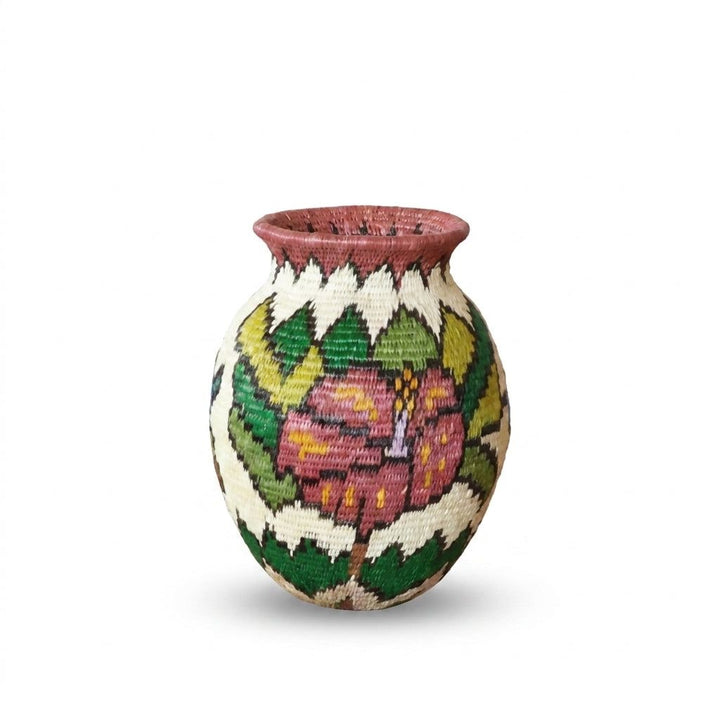 Dusty-pink hibiscus with yellow accents framed by green leaves on rose-rimmed Wounaan handwoven mini basket