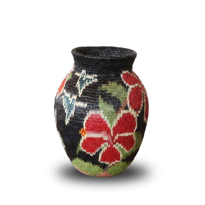 White-rimmed red hibiscus flowers and green leaves glowing on black handwoven Wounaan mini basket from Panama