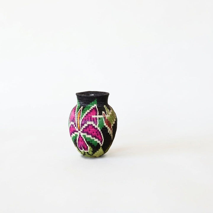Fuchsia and green star bloom with yellow center on black handwoven Wounaan mini basket from Panama