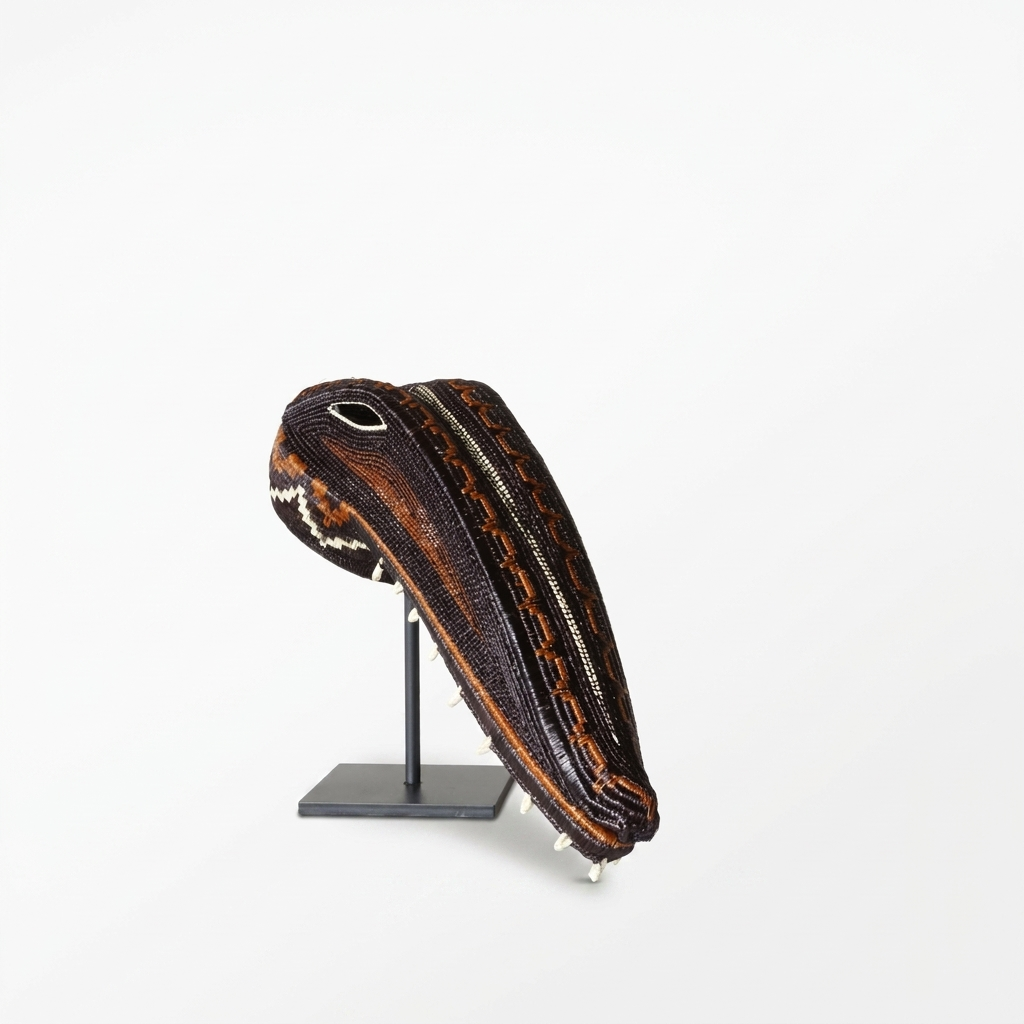Emberá crocodile spirit mask side view showing ridged snout, black-and-cream zigzag and beaded eye, Panama