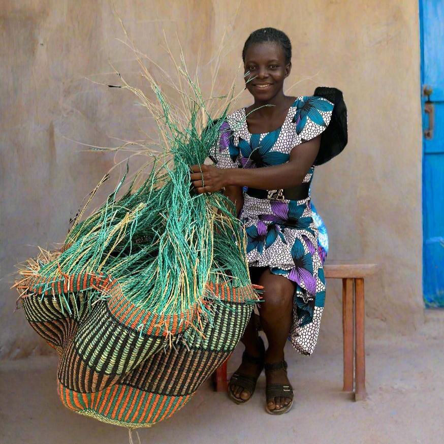 Ghanaian weaver seated holding a large sculptural vessel with a green fibre fringe