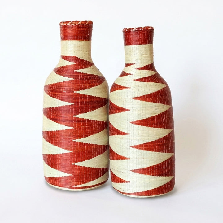 Pair of woven bottle vessels with red and cream zigzag patterns on a white background