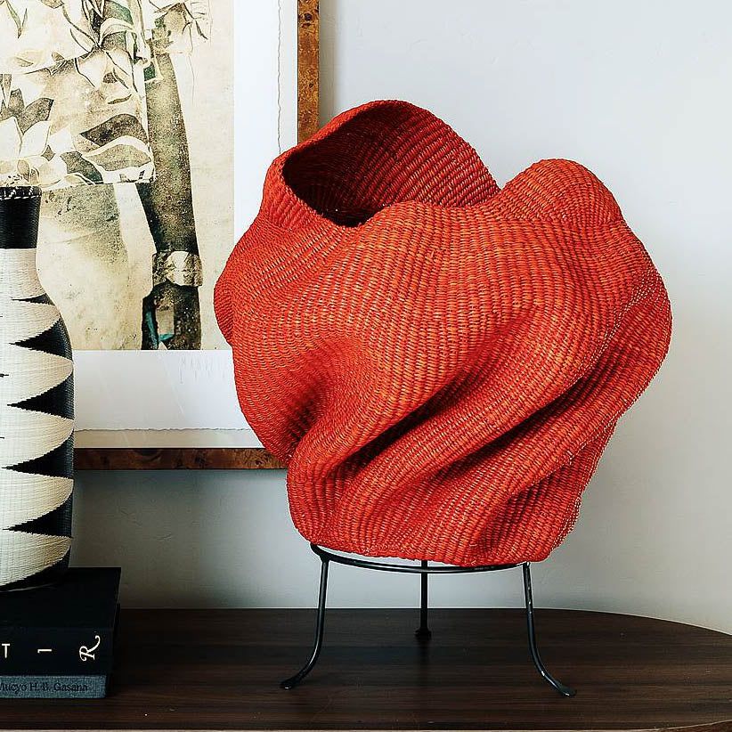 Handmade basket from Ghana in sculptural wave form with rich crimson tones woven from elephant grass