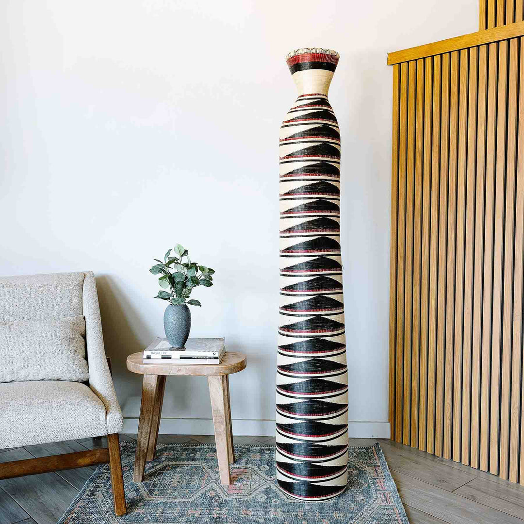 Tall indigo woven basket with geometric tower patterns by Rwandan artisans using elephant grass